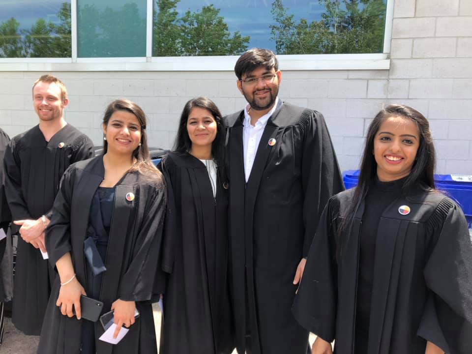 4 graduates in their gowns smiling