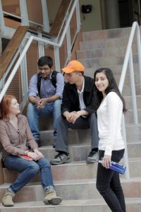 Four Fleming students sitting on a staircase talking and smiling 