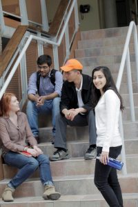 Four Fleming students sitting on a staircase talking and smiling