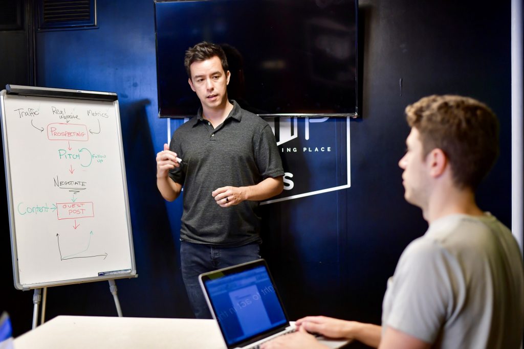 Male faculty teaching student using a whiteboard 