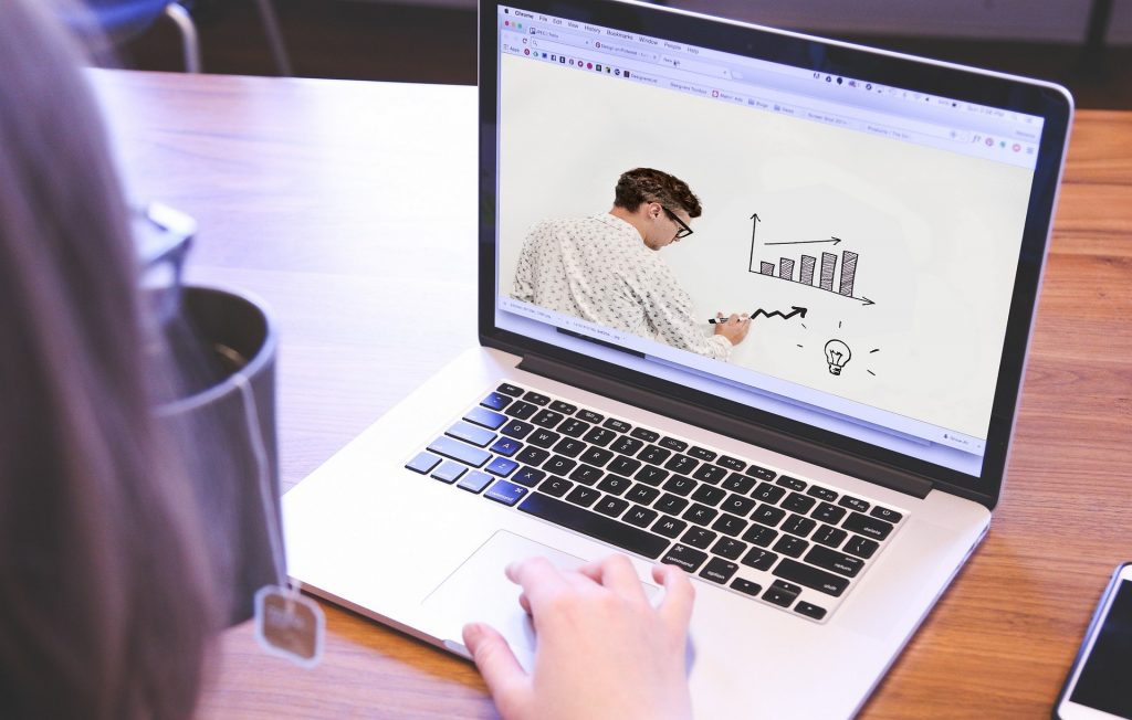 Image of computer showing a teacher on the screen drawing graphs on a whiteboard